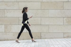 Businesswoman looking at phone while walking